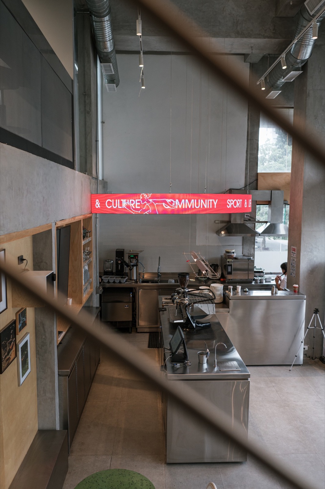 Atlético Café seen through the stair rail: the counter and the round LED sign
