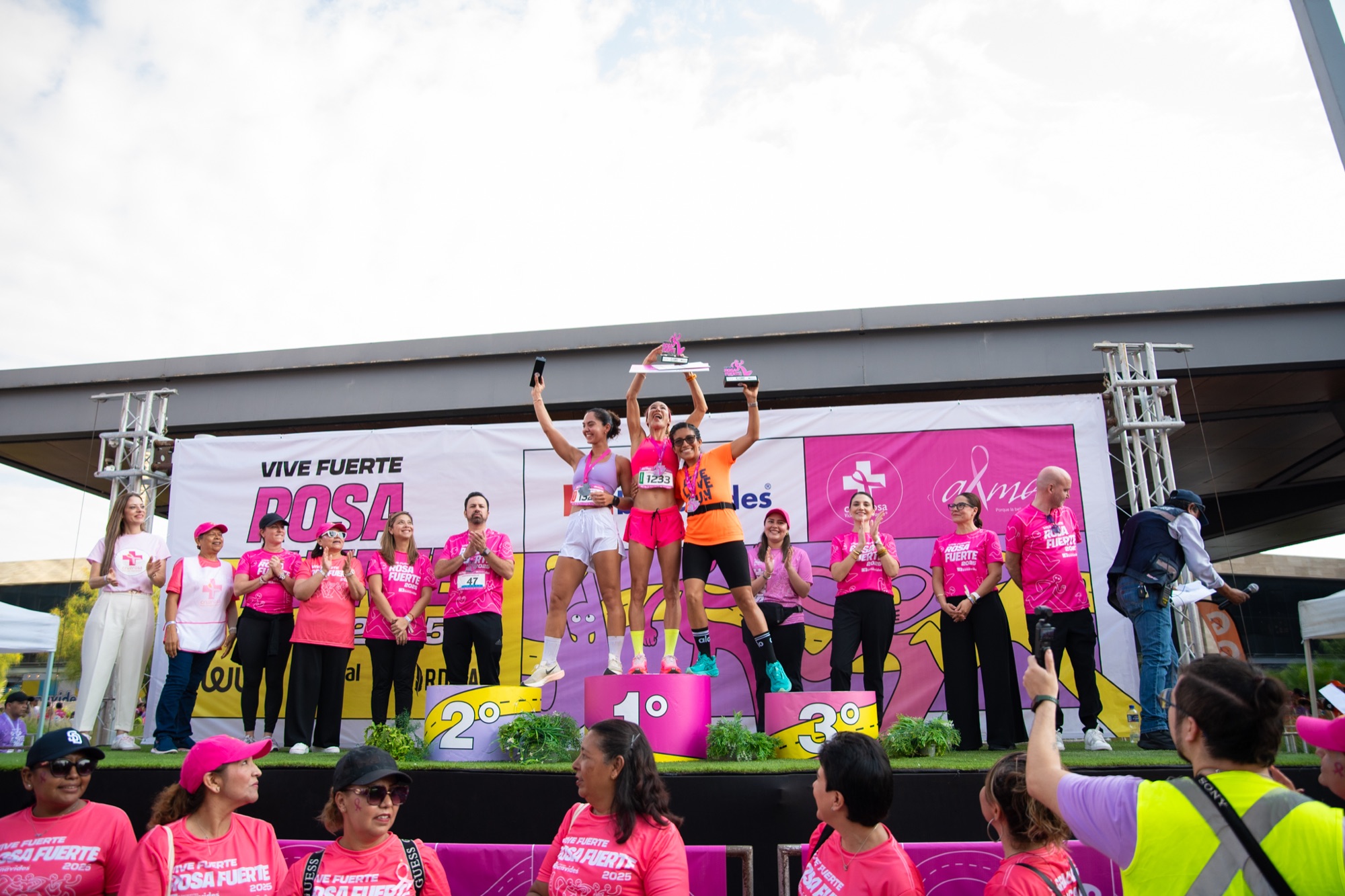 The 2025 podium: three winners holding their trophies up