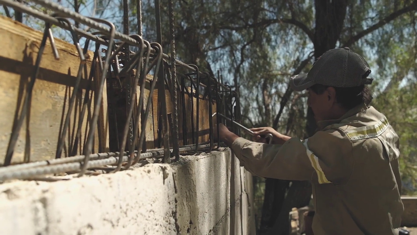 A builder fixing the rebar on top of a block wall